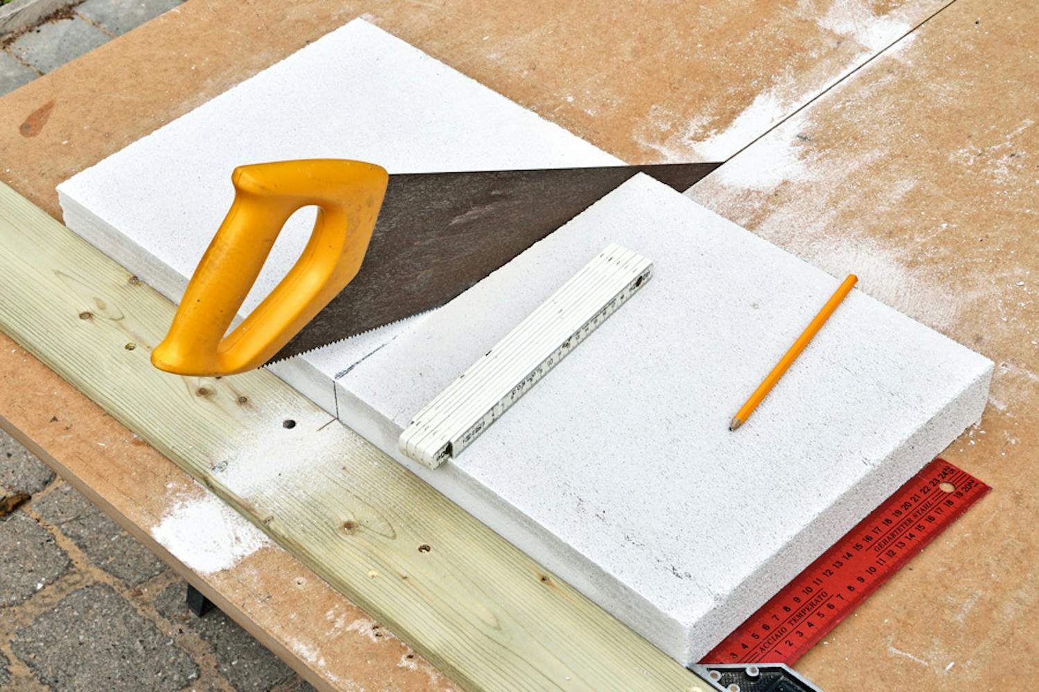 Miten sahaan kevytbetonia? Poikittainen lauta pitää kevytbetonilevyn paikallaan ja helpottaa sahaamista.